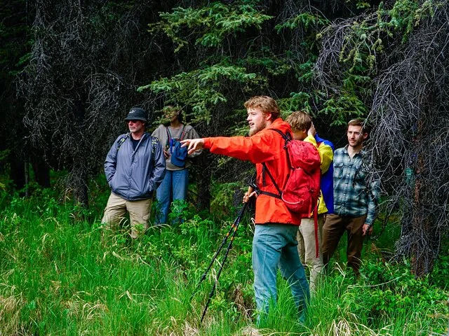 Ein Guide weist einer Gruppe von Wanderern in einem Wald den Weg