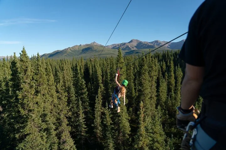 eine Person steht auf einem Felsvorsprung und schaut auf die Berge