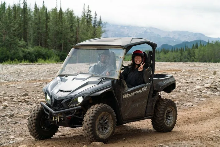 un gruppo di ATV che guida lungo un sentiero sterrato accanto a un ampio fiume