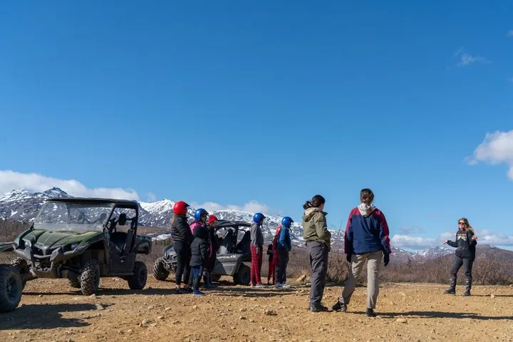 tre persone che viaggiano su un ATV su una strada sterrata